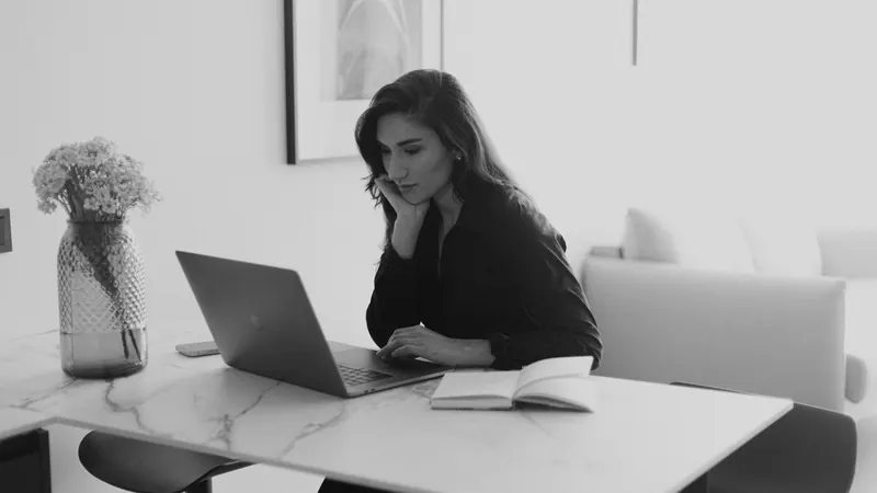 A woman reviewing figures on a laptop in a bright office